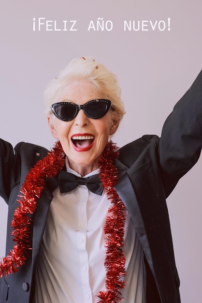 Hermosa y elegante mujer mayor madura con gafas de sol y esmoquin celebrando el año nuevo Fiesta divertida