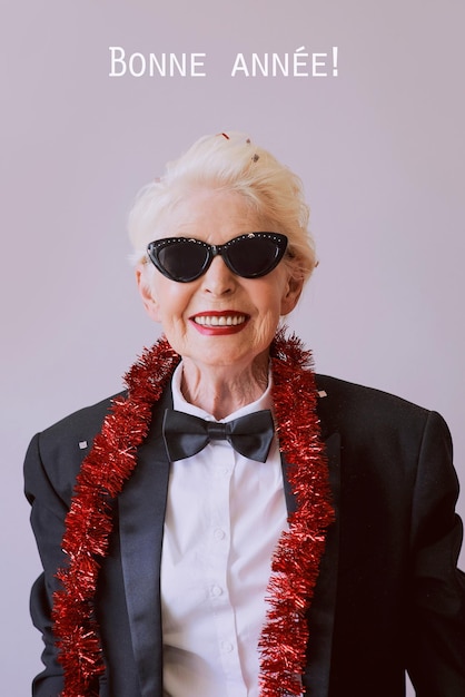 Hermosa y elegante mujer mayor madura con gafas de sol y esmoquin celebrando el año nuevo Fiesta divertida