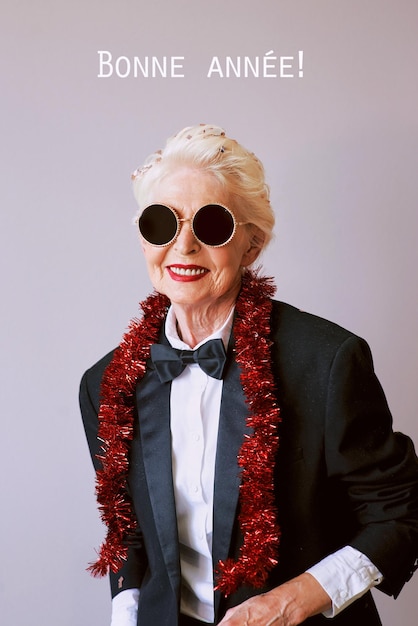 Hermosa y elegante mujer mayor madura con gafas de sol y esmoquin celebrando el año nuevo Fiesta divertida