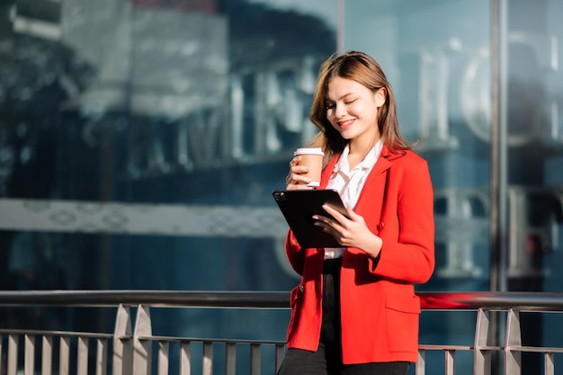 Hermosa empresaria asiática escribiendo computadora portátil y tableta digital mientras toma café en la oficina Trabajador de oficina en el centro de negocios