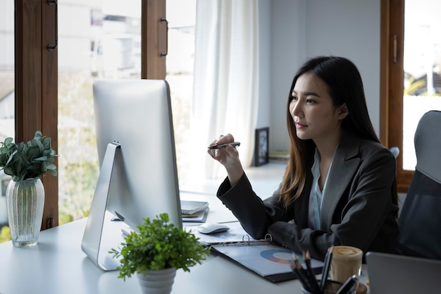 Hermosa empresaria asiática que trabaja con una computadora en un lugar de trabajo moderno.