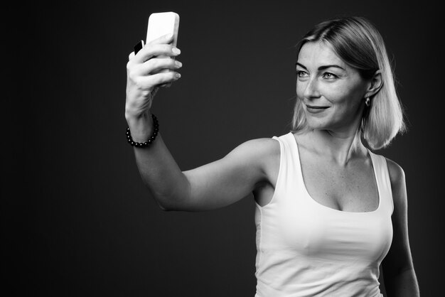 Hermosa empresaria con pelo corto tomando selfie con teléfono