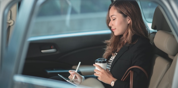 Hermosa empresaria profesional trabajando en el automóvil mientras se dirige a la oficina