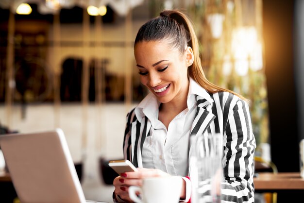 Hermosa empresaria en traje de moda sonriendo alegremente leyendo mensajes de texto