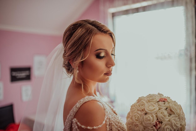 Una hermosa y encantadora novia morena preparándose por la mañana en la habitación