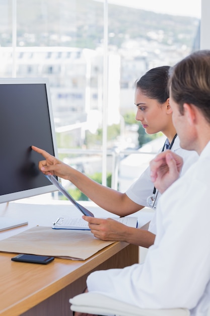 Hermosa enfermera mostrando la pantalla de una computadora a un colega