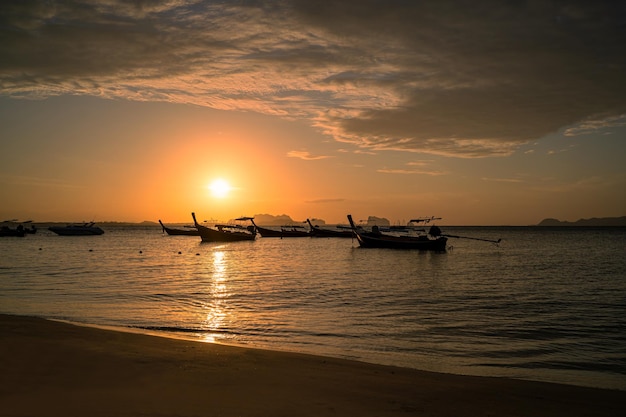 Hermosa escena durante la puesta de sol con la silueta de un bote de cola larga en el fondo