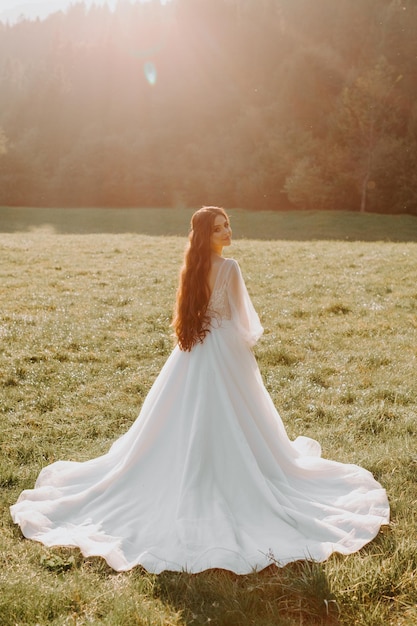 Hermosa espalda de la novia con un vestido de novia en el campo al atardecer