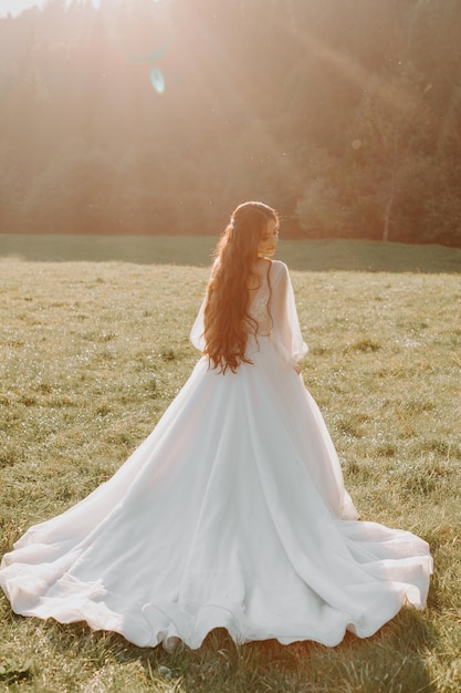 Hermosa espalda de la novia con un vestido de novia en el campo al atardecer