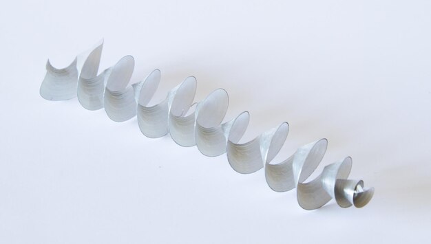 Una hermosa espiral de metal de la perforación en un fondo blanco