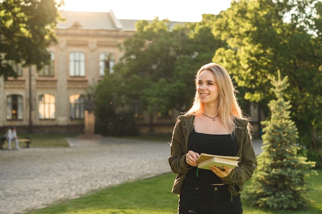 Hermosa estudiante con amplia sonrisa sosteniendo cuadernos