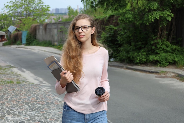 Hermosa estudiante con anteojos yendo a casa de la escuela