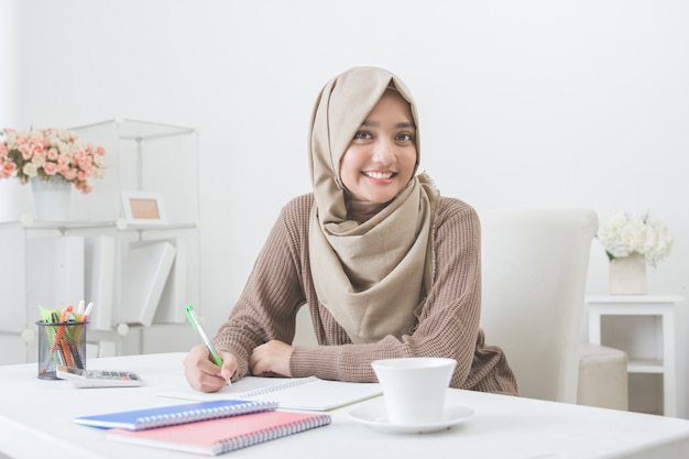 Hermosa estudiante asiática con hijab haciendo la tarea