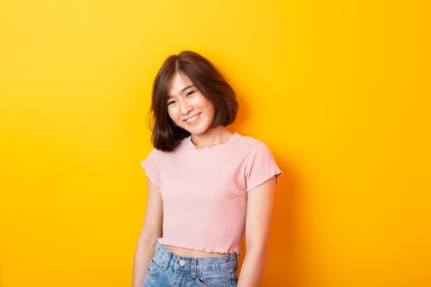 Hermosa estudiante asiática en pared amarilla