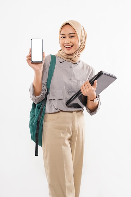 Una hermosa estudiante con hiyab de pie mostrando el teléfono