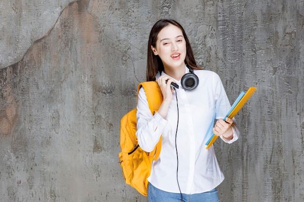 Hermosa estudiante con mochila y auriculares cargando libros. foto de alta calidad