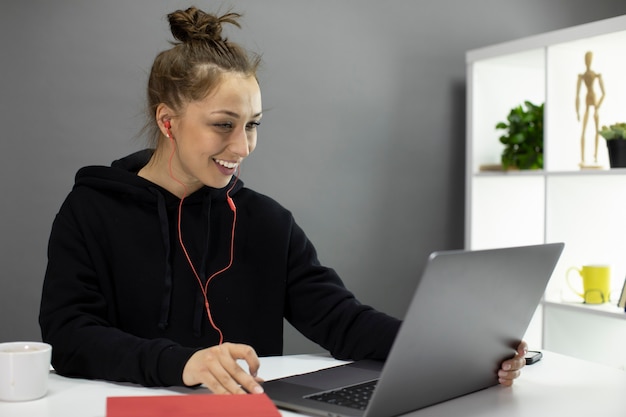 Hermosa estudiante sonriente en auriculares estudia en línea, concepto de educación distante