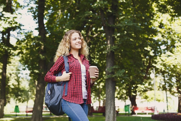 Hermosa estudiante sonriente bebiendo café en el parque del campus. Concepto de educación, espacio de copia