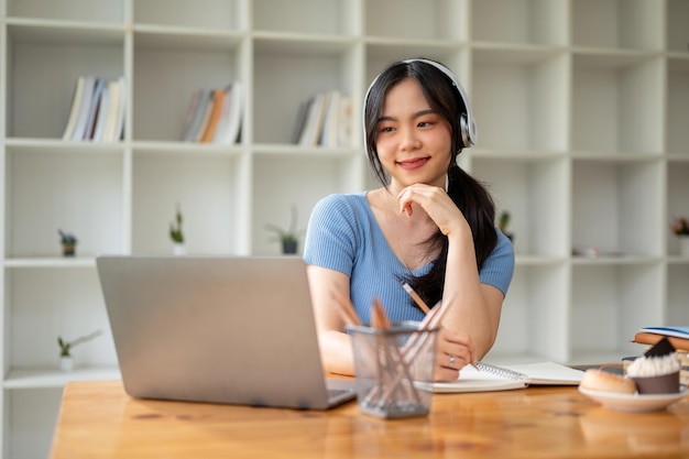 Una hermosa estudiante universitaria asiática sonríe mientras escucha música a través de sus auriculares