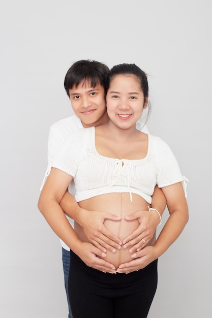 Hermosa familia asiática retrato de marido y mujer feliz esperando un bebé en la pared blanca