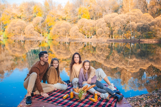 Hermosa familia en un cálido día de otoño cerca del lago