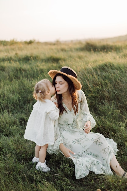 Hermosa familia caucásica de padre, madre e hija pequeña posando en la cámara en el fondo del campo verde