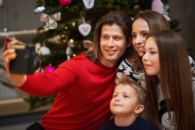 Hermosa familia celebrando la Navidad en casa y tomando fotografías instantáneas