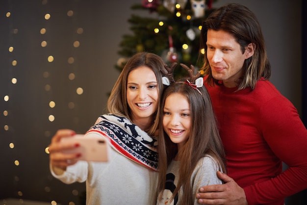 Hermosa familia celebrando la Navidad en casa y tomando selfie