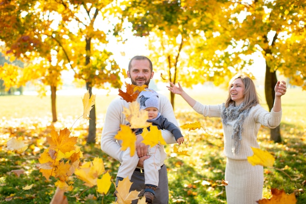 Hermosa familia divirtiéndose con su hijo en el parque otoño.