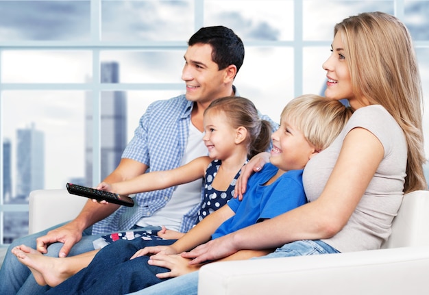 Hermosa familia encantadora sonriente viendo la televisión en el fondo