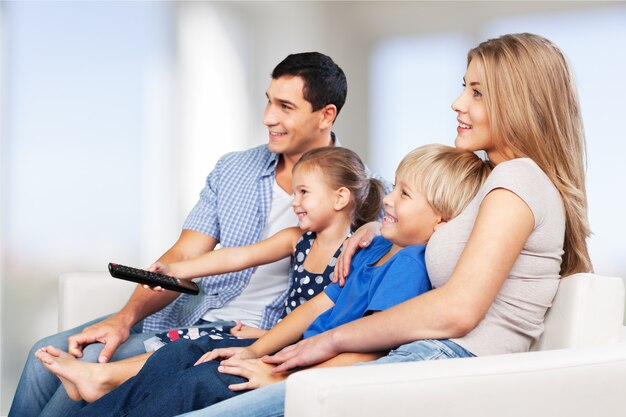 Hermosa familia encantadora sonriente viendo la televisión en el fondo