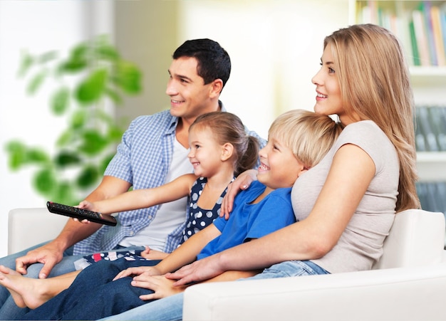 Hermosa familia encantadora sonriente viendo la televisión en el fondo