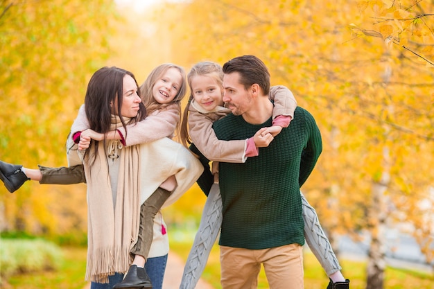 Hermosa familia feliz de cuatro en otoño día al aire libre