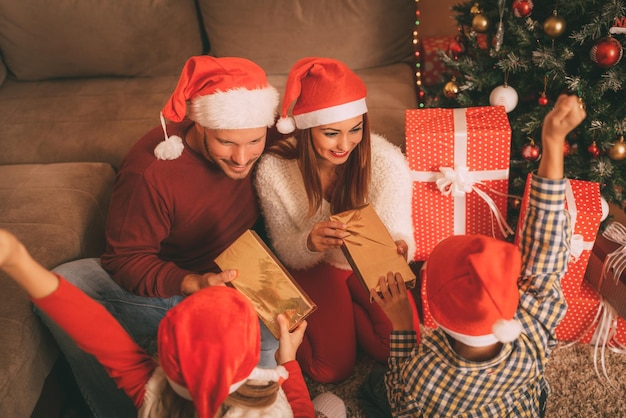 Hermosa familia feliz con sombrero de santa e intercambiando regalos de Navidad en casa. Enfoque selectivo.