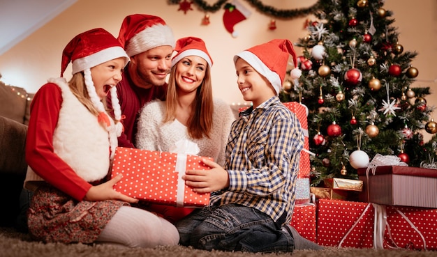 Hermosa familia feliz con sombrero de santa y se sorprenden con regalos de Navidad en casa.
