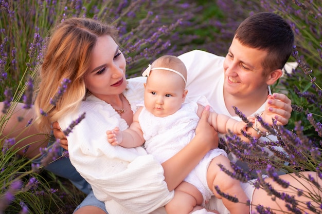 Hermosa familia joven en el campo de lavanda de flor morada. Vacaciones familiares