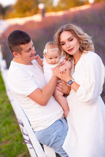 Hermosa familia joven en el campo de lavanda de flor morada. Vacaciones familiares