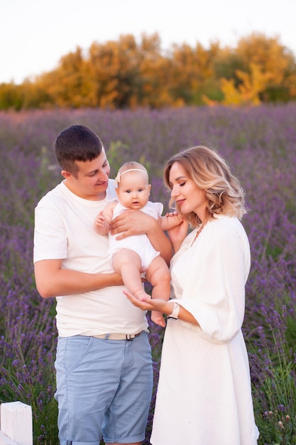 Hermosa familia joven en el campo de lavanda de flor morada. Vacaciones familiares