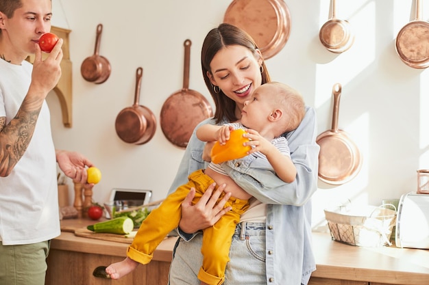 Una hermosa familia joven con un niño cocina juntos