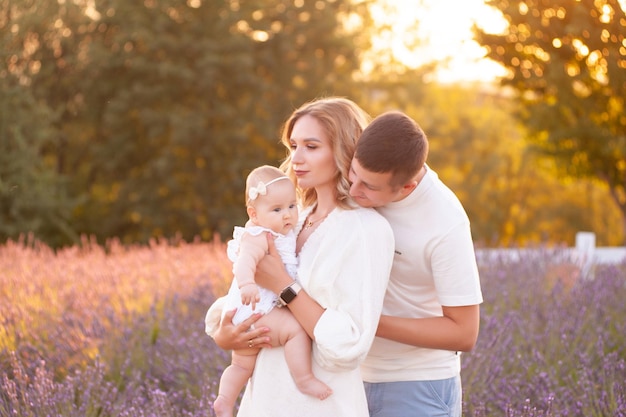 Hermosa familia joven, padre y madre con una hija pequeña jugando en el campo de lavanda