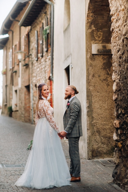 Hermosa familia con paseos en el casco antiguo de Sirmione en Italia. Una pareja paseando por la antigua Italia.