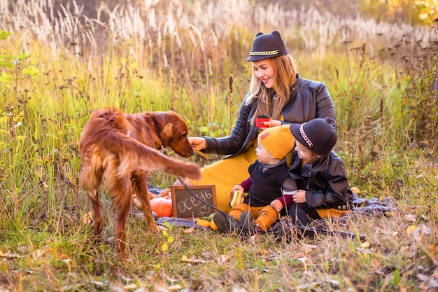 Hermosa familia con un perro golden retriever en un paseo en la naturaleza soleada de otoño