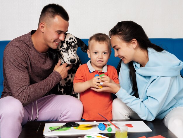 Hermosa familia con un perro pintando con su hijo.