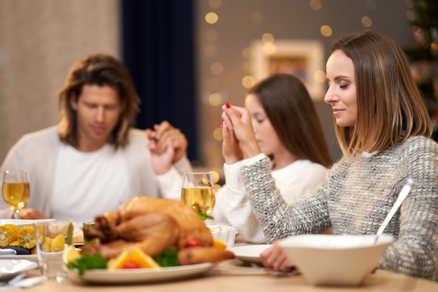 hermosa familia rezando durante la cena navideña