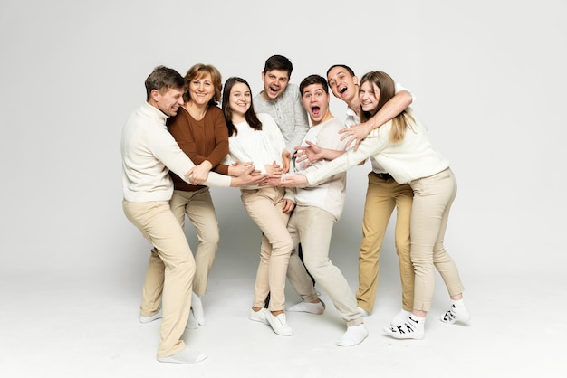 Hermosa familia riendo y divirtiéndose en un fondo blanco. los miembros de la familia abrazan a una niña embarazada. familia de mediana edad. gente de veinte y treinta años.