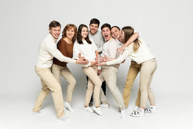 Hermosa familia riendo y divirtiéndose en un fondo blanco. los miembros de la familia abrazan a una niña embarazada. familia de mediana edad. gente de veinte y treinta años.