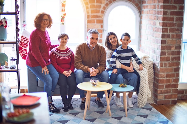 Hermosa familia sonriendo feliz y confiada. Sentado en el sofá y posando celebrando la navidad en casa