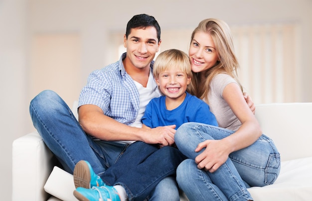 Hermosa familia sonriente sentada en el sofá en casa