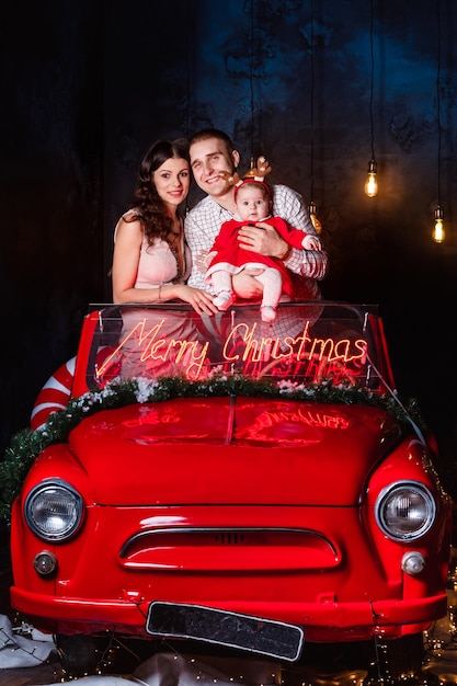 Hermosa familia con su bebé en un auto retro