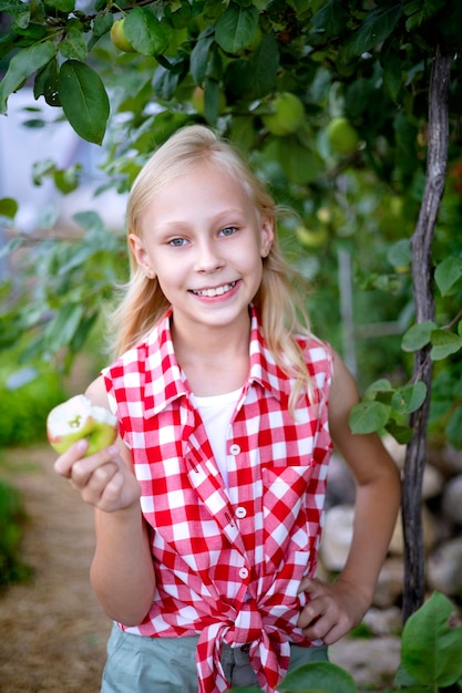 Una hermosa y feliz chica rubia en un huerto de manzanas
